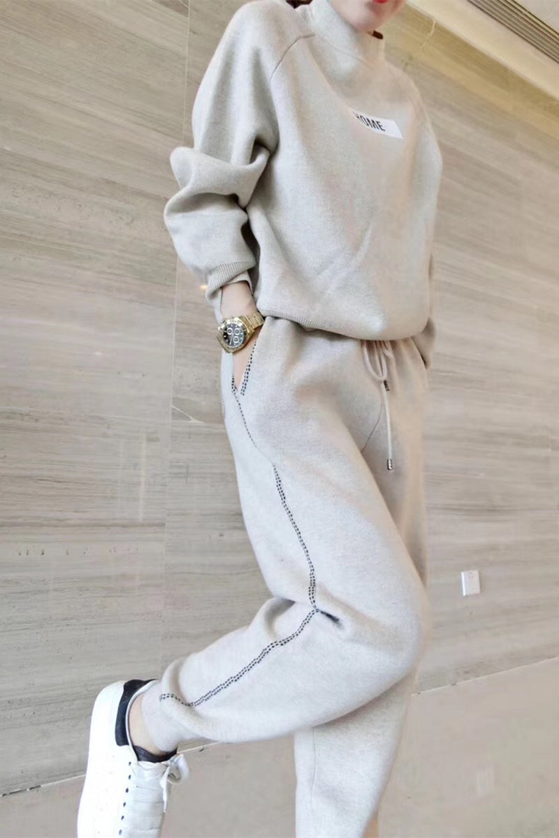Femme portant l'ensemble en tricot et cachemire gris clair, sweat-shirt à écusson HOME et pantalon assorti, vue en pied en marchant