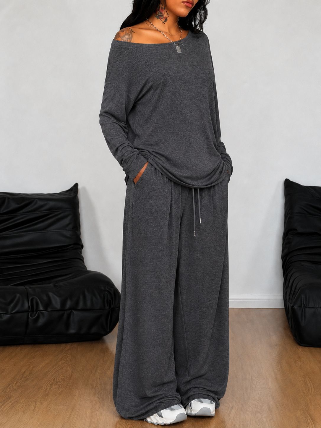 Ensemble t-shirt et pantalon large gris foncé, porté, mains dans les poches, tatouages visibles, vue de face