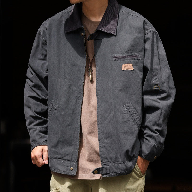 Veste de travail en toile de coton gris foncé, portée par un modèle, vue de face sur fond noir