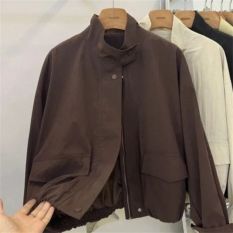Veste coupe-vent col montant marron, détail de l'ourlet élastique, sur cintre