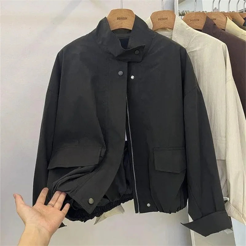 Veste coupe-vent col montant noire, ouverte, sur cintre, vue de face