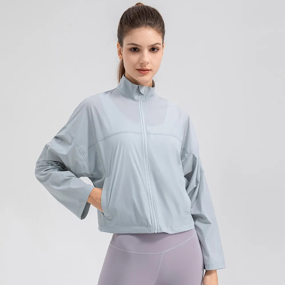 Veste légère anti-UV bleue zippée courte, portée, main sur la hanche, vue de face sur fond blanc