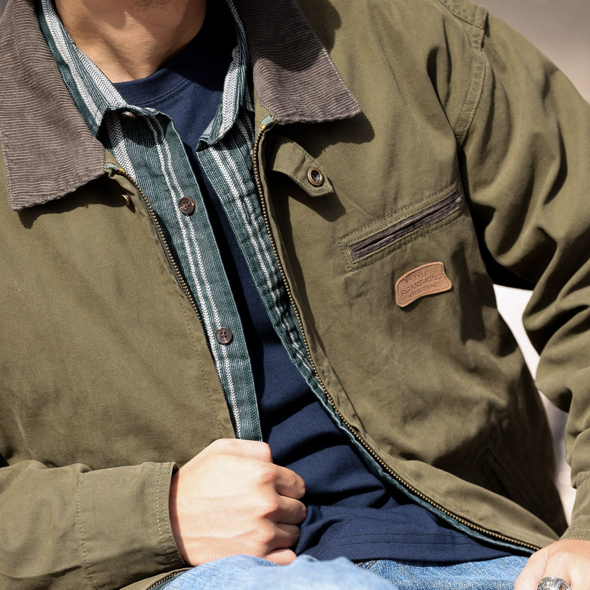 Veste de travail en toile de coton kaki, détail du col chemise et de la poitrine, portée par un modèle