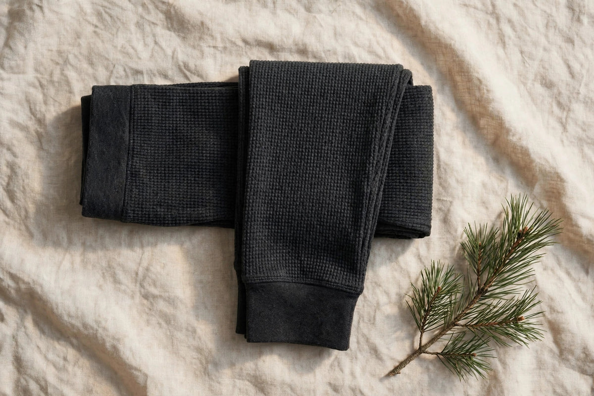 Legging thermique en laine mérinos noir-gris – présenté à plat sur lin écru